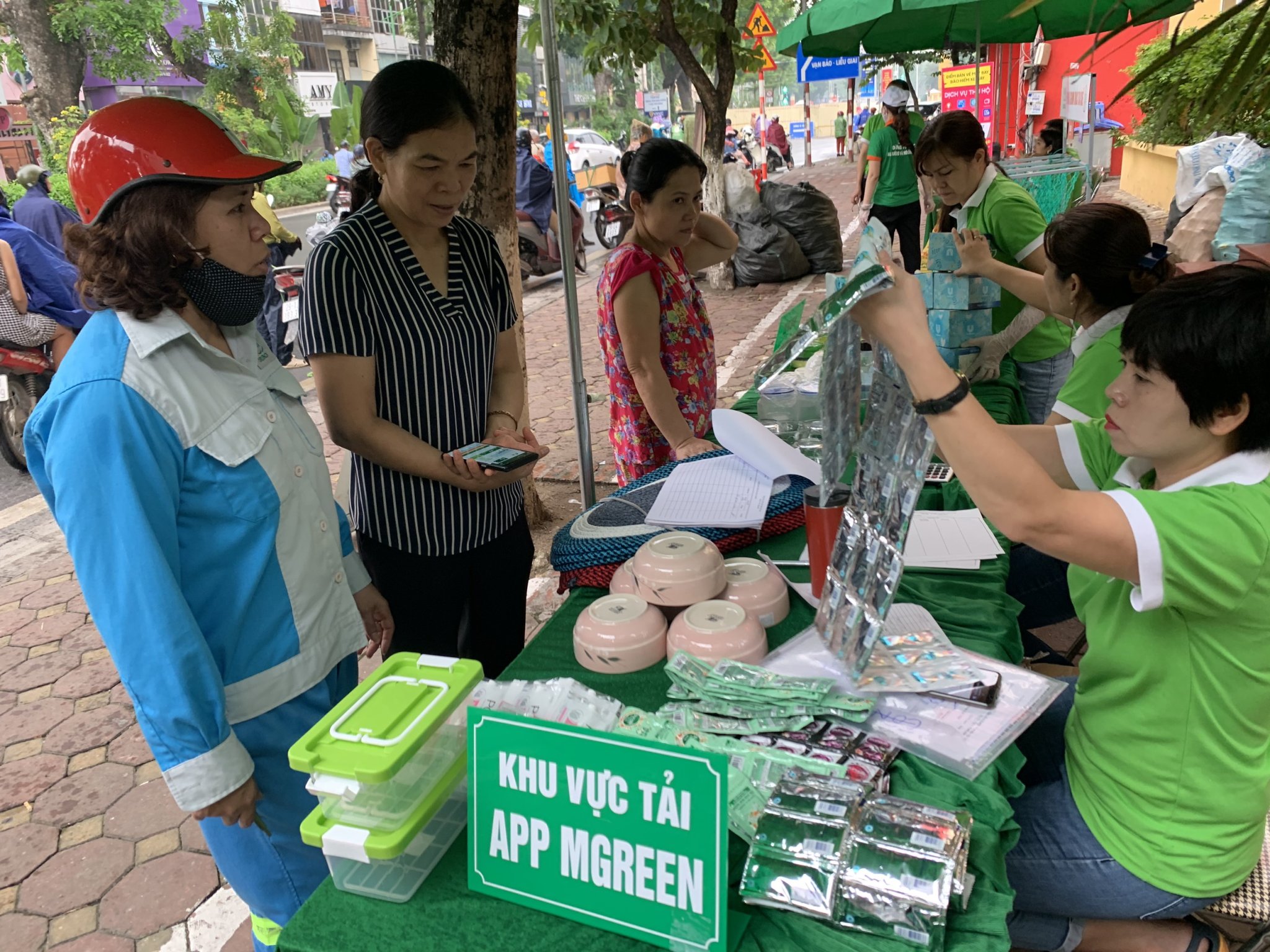 Người dân sử dụng App mGreen để tích điểm khối lượng rác tái chế và nhận quà tại các Điểm (GreenHub) cân rác đổi quà của mGreen tại Phường Lý Thái Tổ, quận Hoàng Kiếm